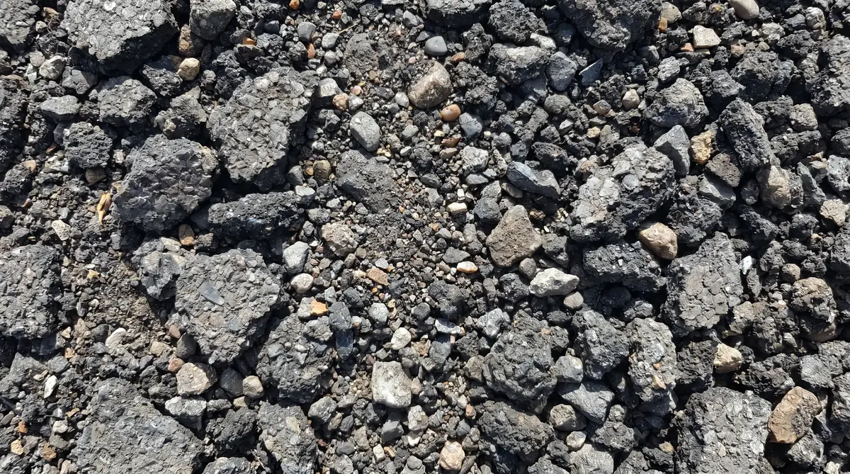 Close-up of recycled asphalt millings showing dark gray chunky texture with small aggregate