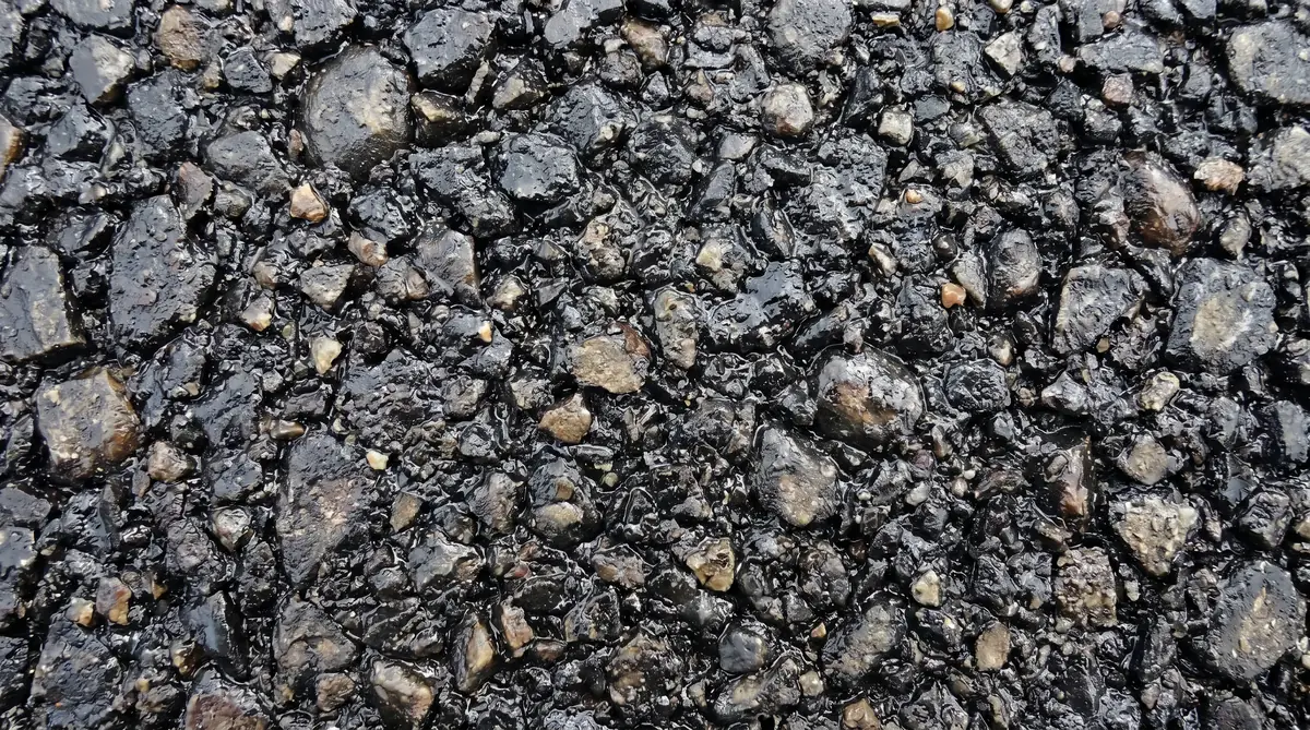 Macro close-up of dense-graded asphaltic concrete showing aggregate particles coated in black asphalt binder